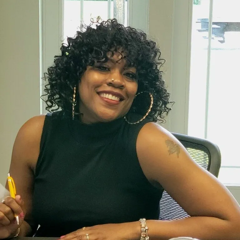 A woman with curly hair sitting at a desk.