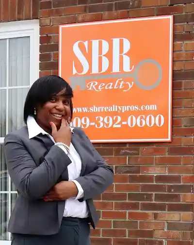 A woman standing in front of a brick building.