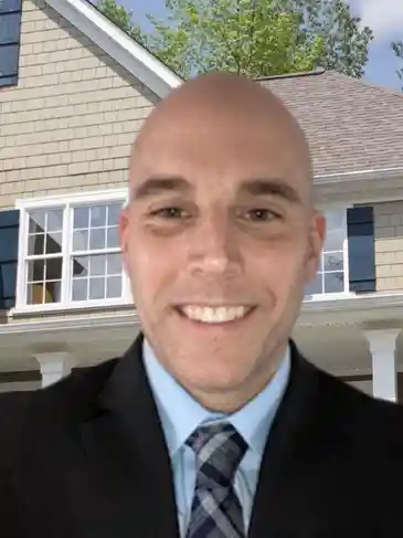 A man in suit and tie standing outside of a house.