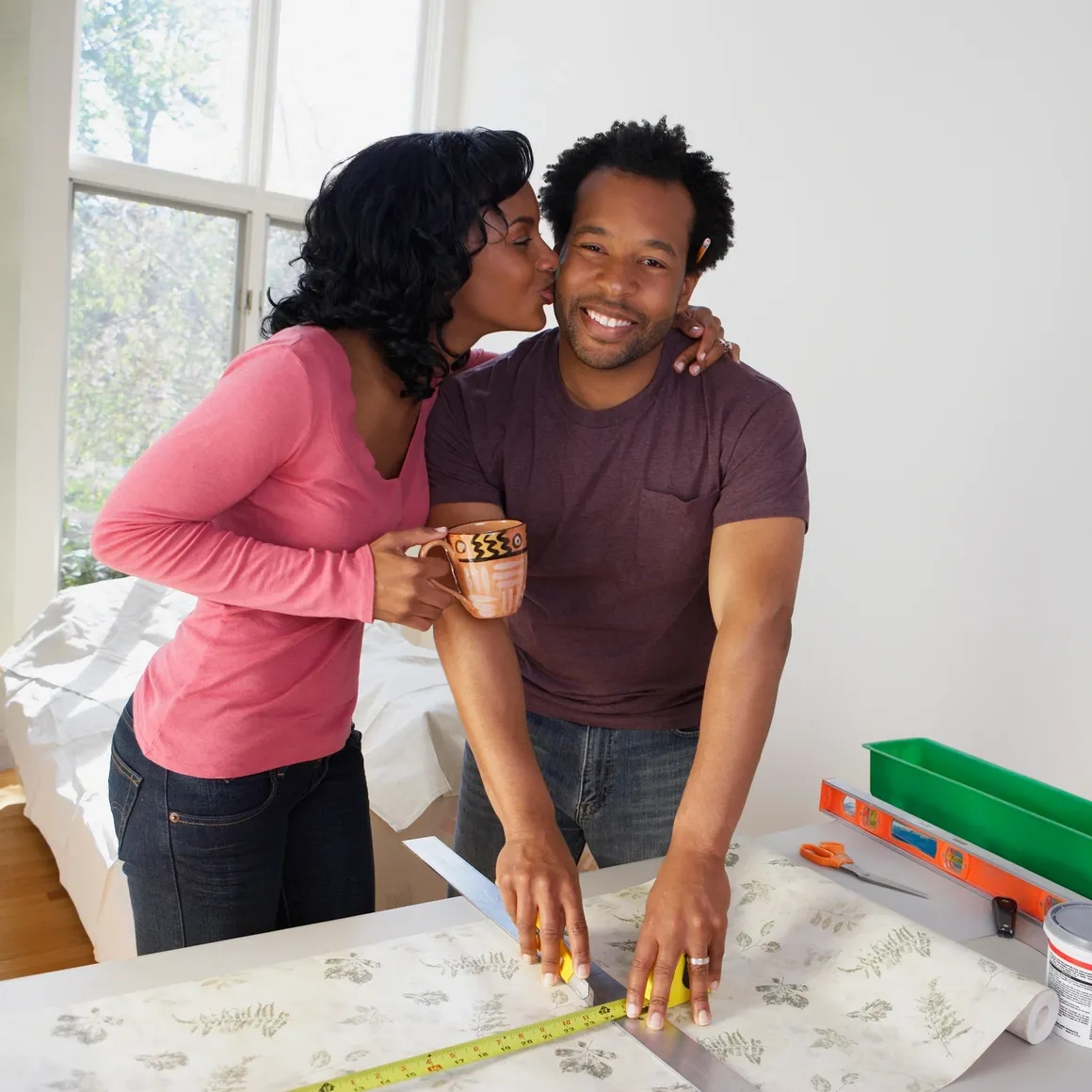 A man and woman are kissing in front of a table.