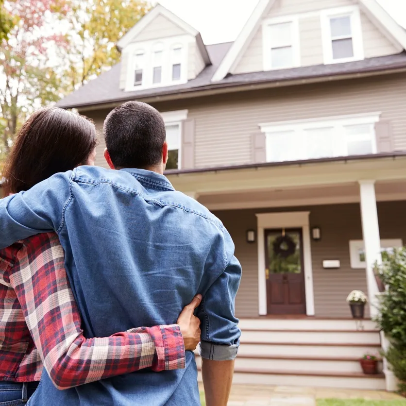 A man and woman standing in front of a house.