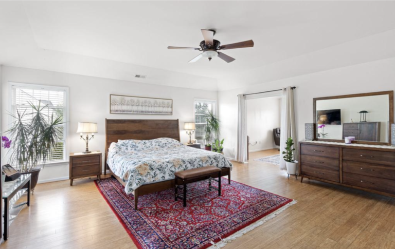 A bedroom with a bed, dresser and ceiling fan.