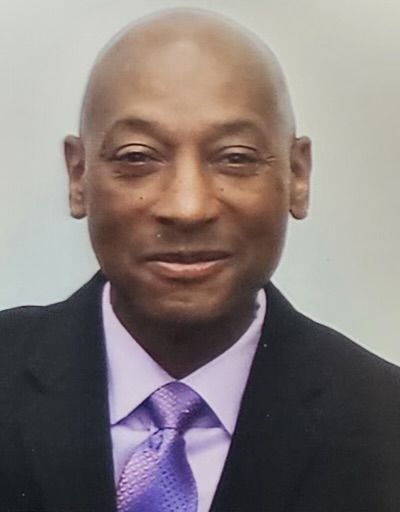 A man in a suit and tie smiling for the camera.