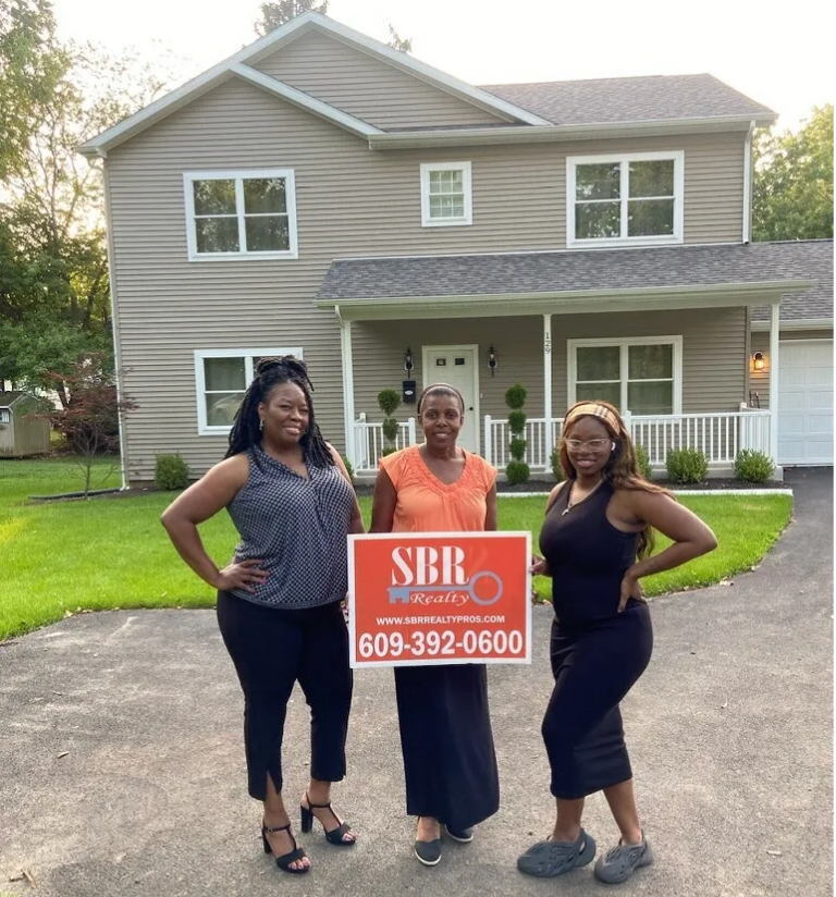 Three women standing in front of a house